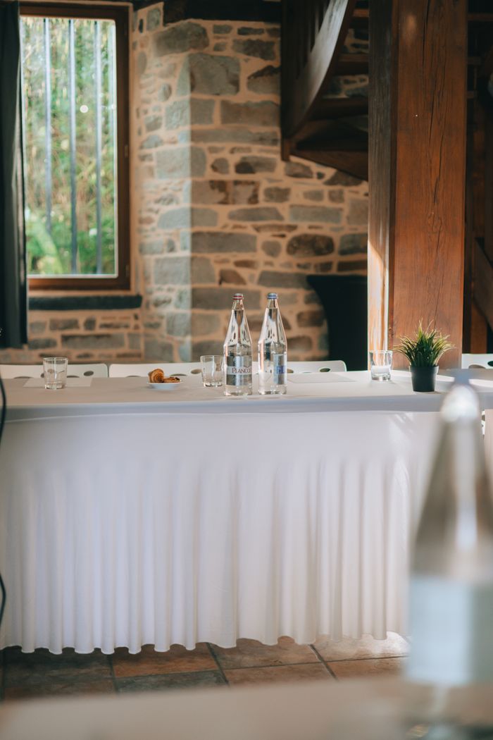 A sophisticated indoor conference setup with water bottles and glassware on a white table.